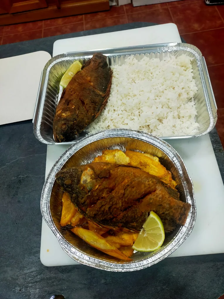 Pescado con arroz blanco, patatas y limones para gotear el pescado.